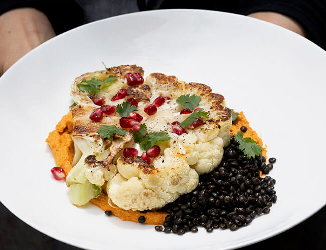 Roasted cauliflower with black beans and pomegranate and cilantro garnish