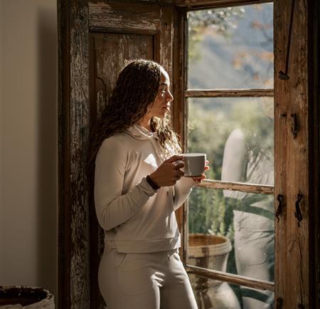 woman looking out of window with coffee