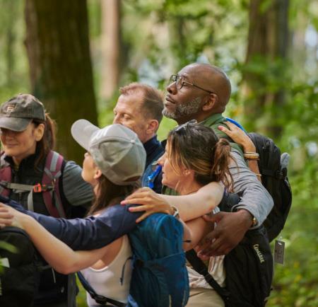 A group of people having a group hug on a hike