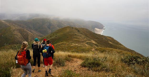 Group of hikers walking down path with an ocean view