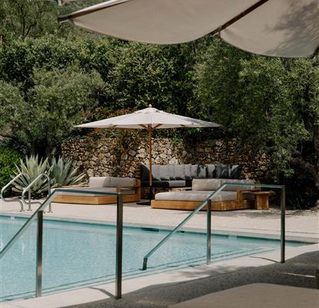 Pool on a sunny day with shade umbrellas and lounge chairs and a view of the mountains