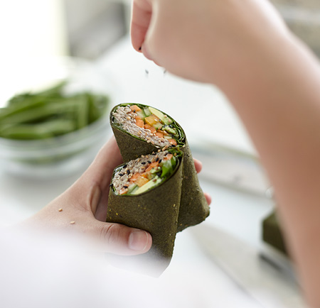 Chef adding sesame seed garnish to a veggie wrap