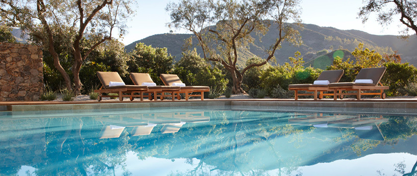 The pool is surrounded by lounge chairs with colorful umbrellas