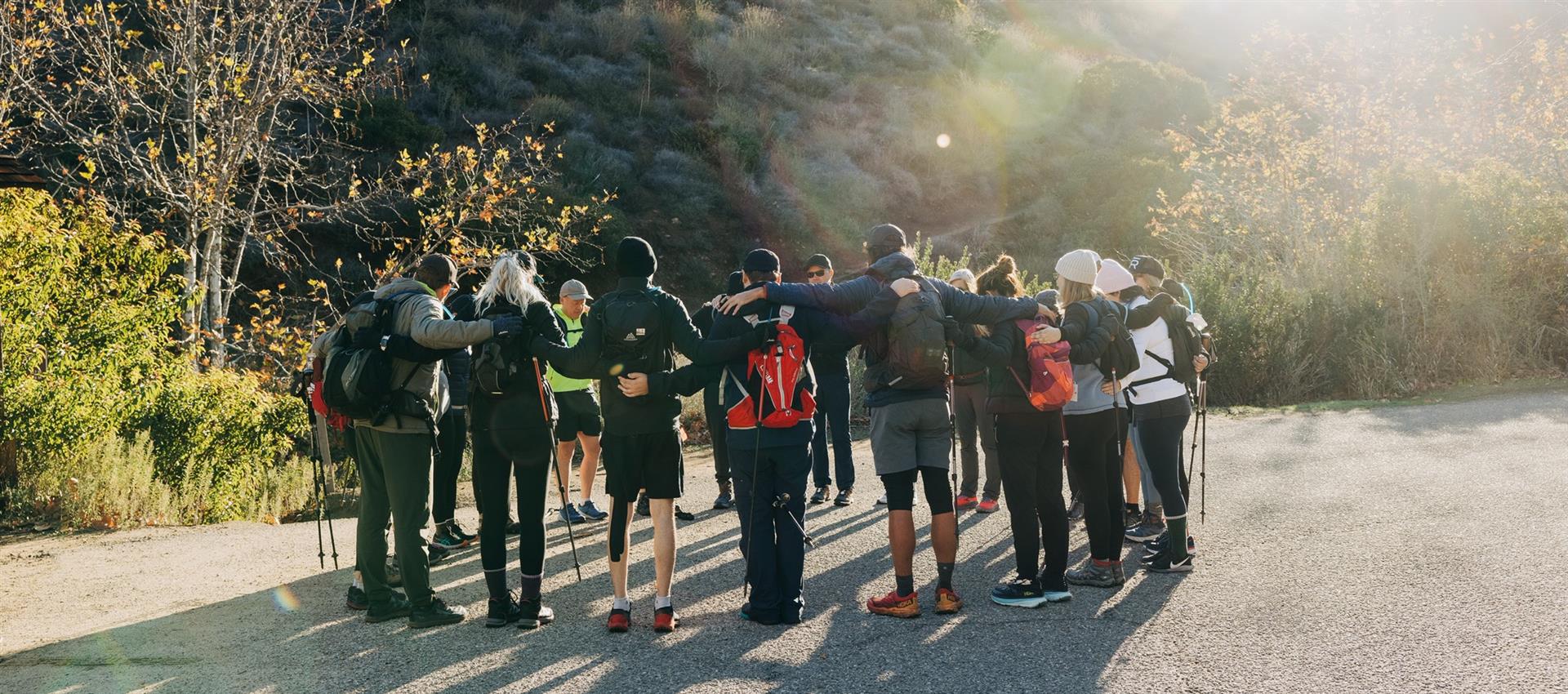 Group of people standing in a circle with hiking sticks in a natural outdoor setting.